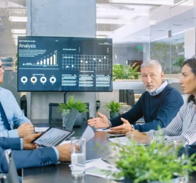 people meeting around table with large monitor at end