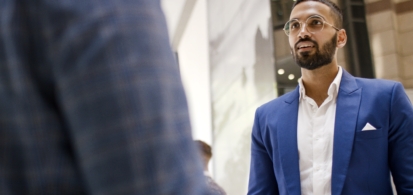 Two business people talking, wearing suits, including a man of Indian descent